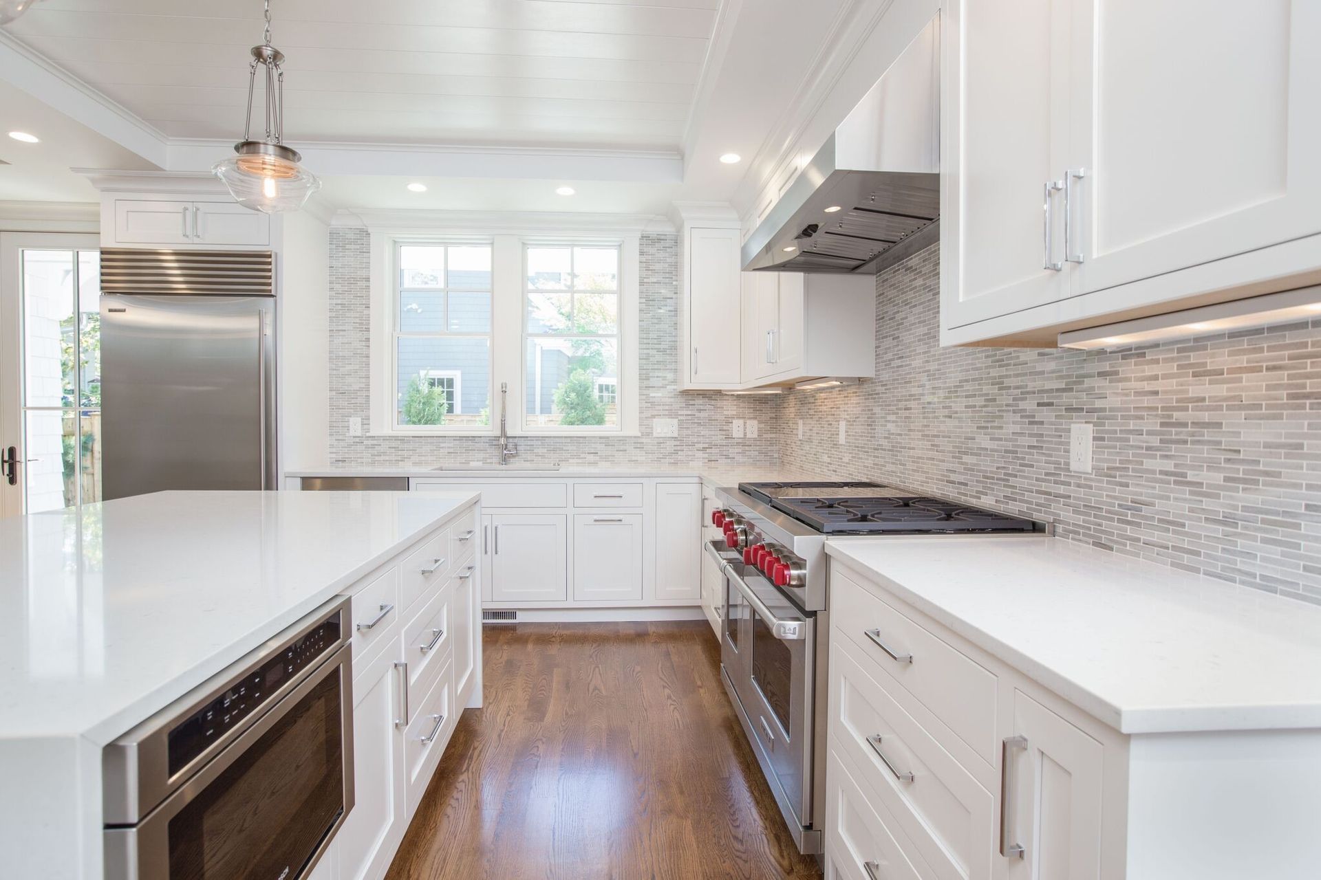 A kitchen with white cabinets , stainless steel appliances , and hardwood floors.