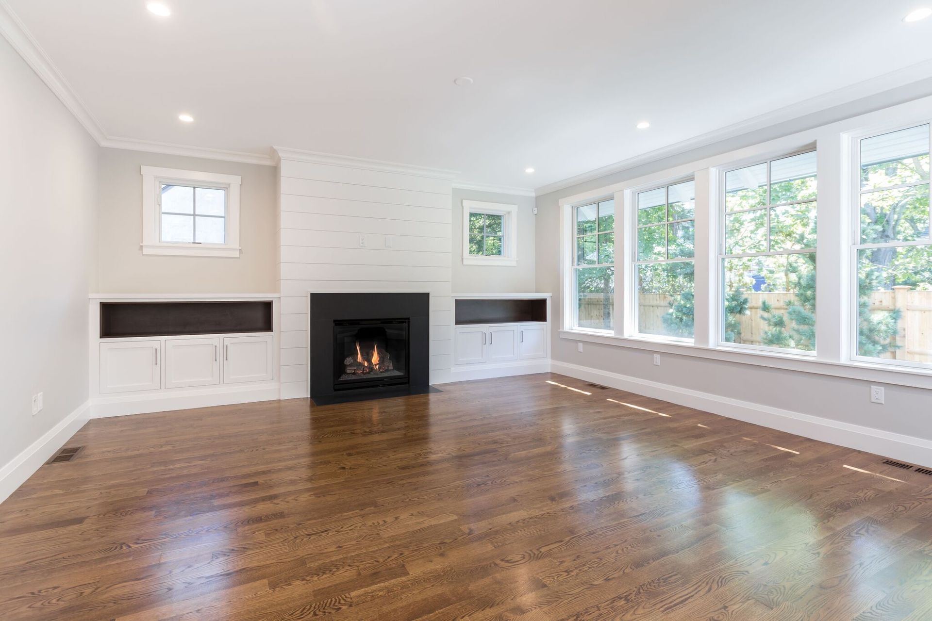 An empty living room with hardwood floors and a fireplace.