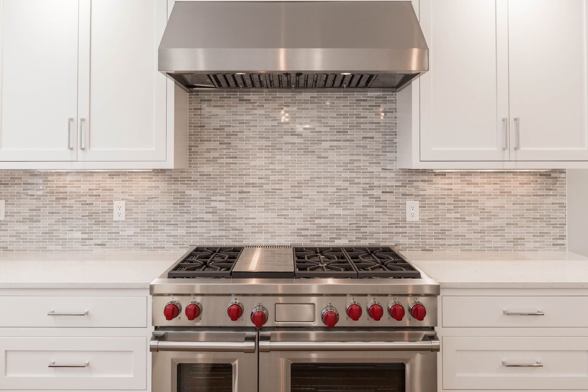 A stainless steel stove and oven in a kitchen with white cabinets.