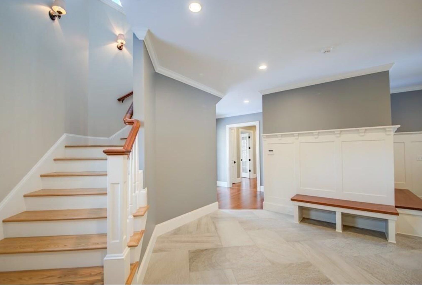 A hallway with stairs and a bench in it