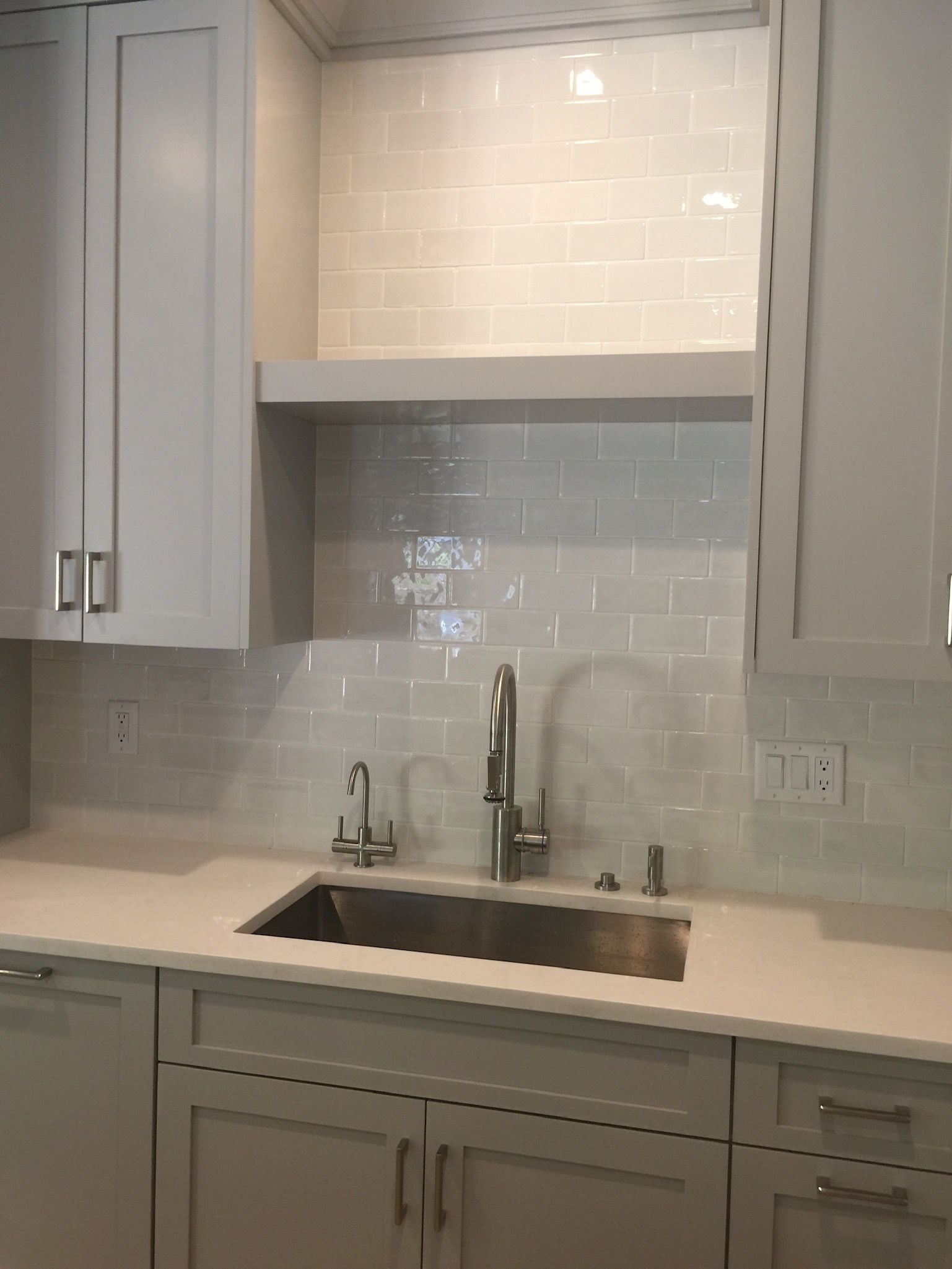 A kitchen with gray cabinets and a sink with a faucet.