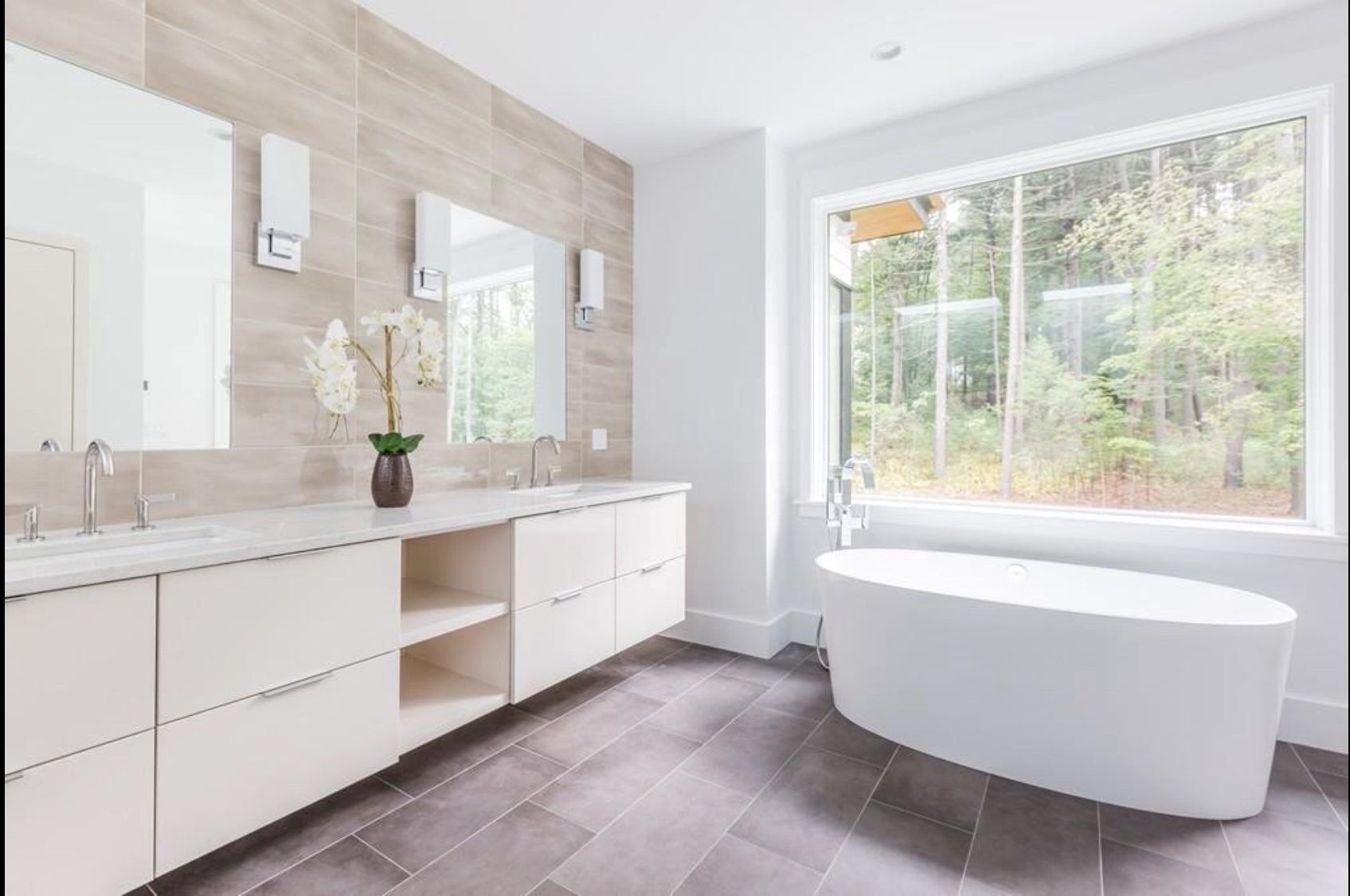 A bathroom with two sinks , a tub and a large window.