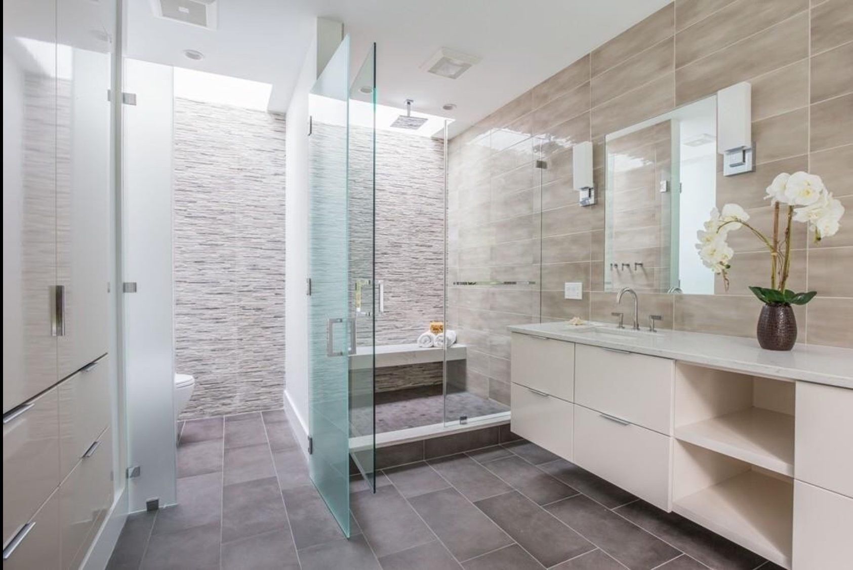 A bathroom with a walk in shower , sink and mirror.
