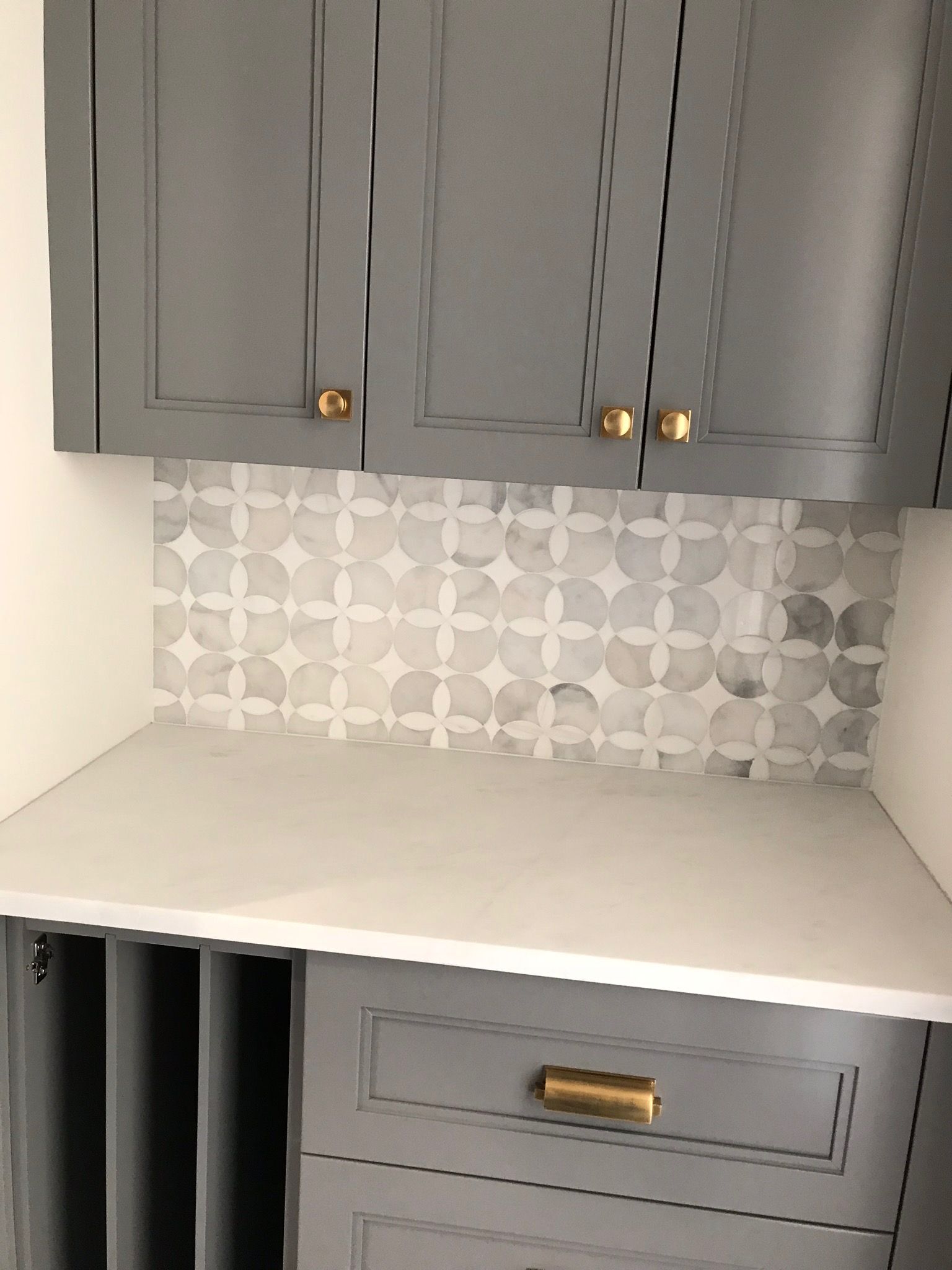 A kitchen with gray cabinets and a white counter top.
