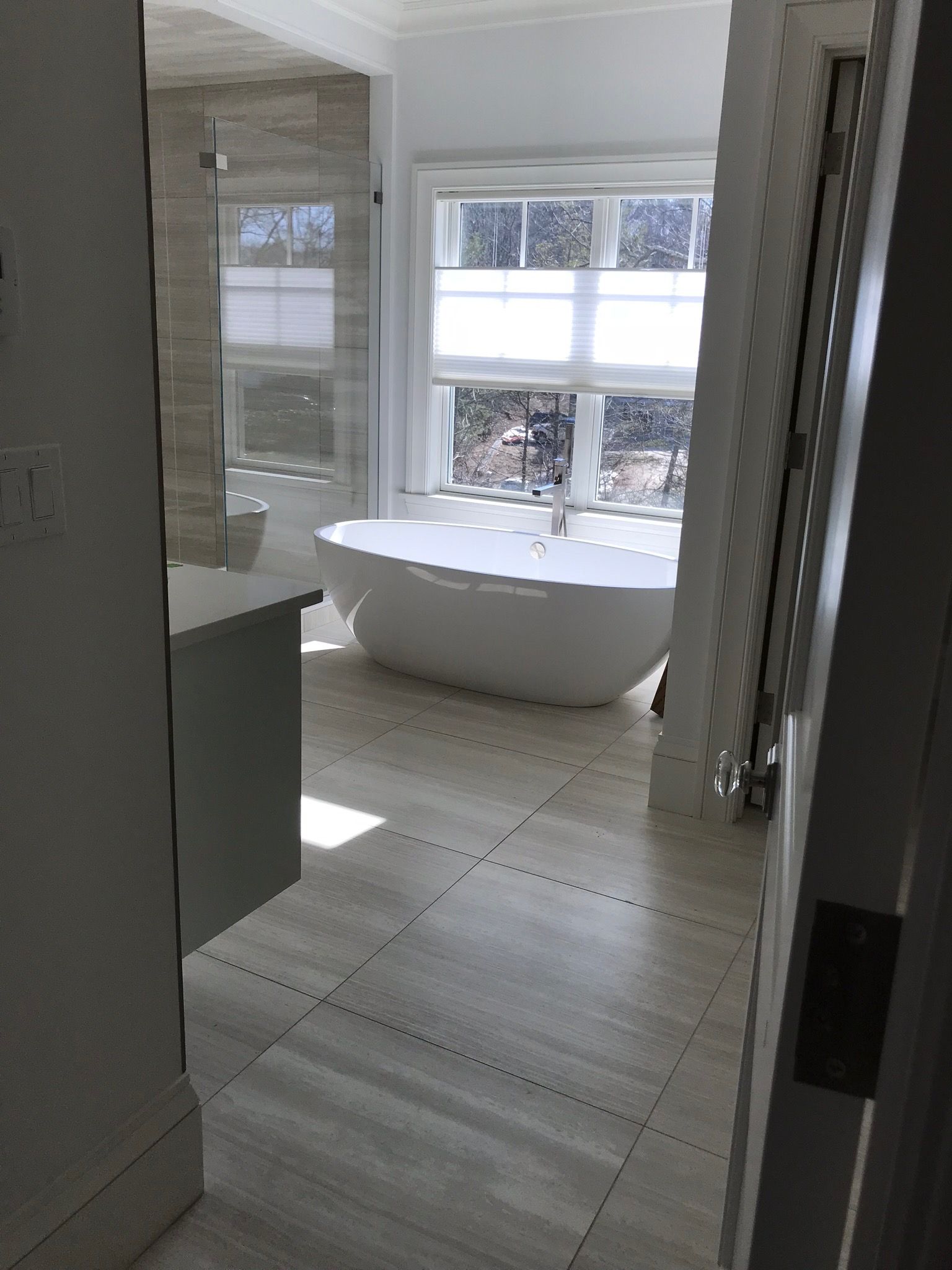 A bathroom with a tub , sink , and window.