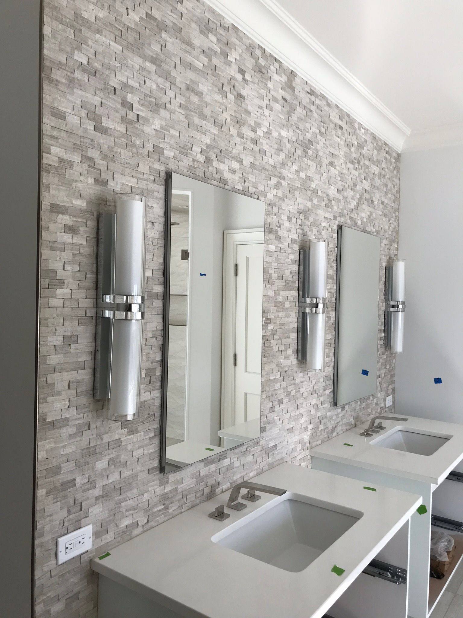 A bathroom with two sinks , two mirrors , and a tiled wall.
