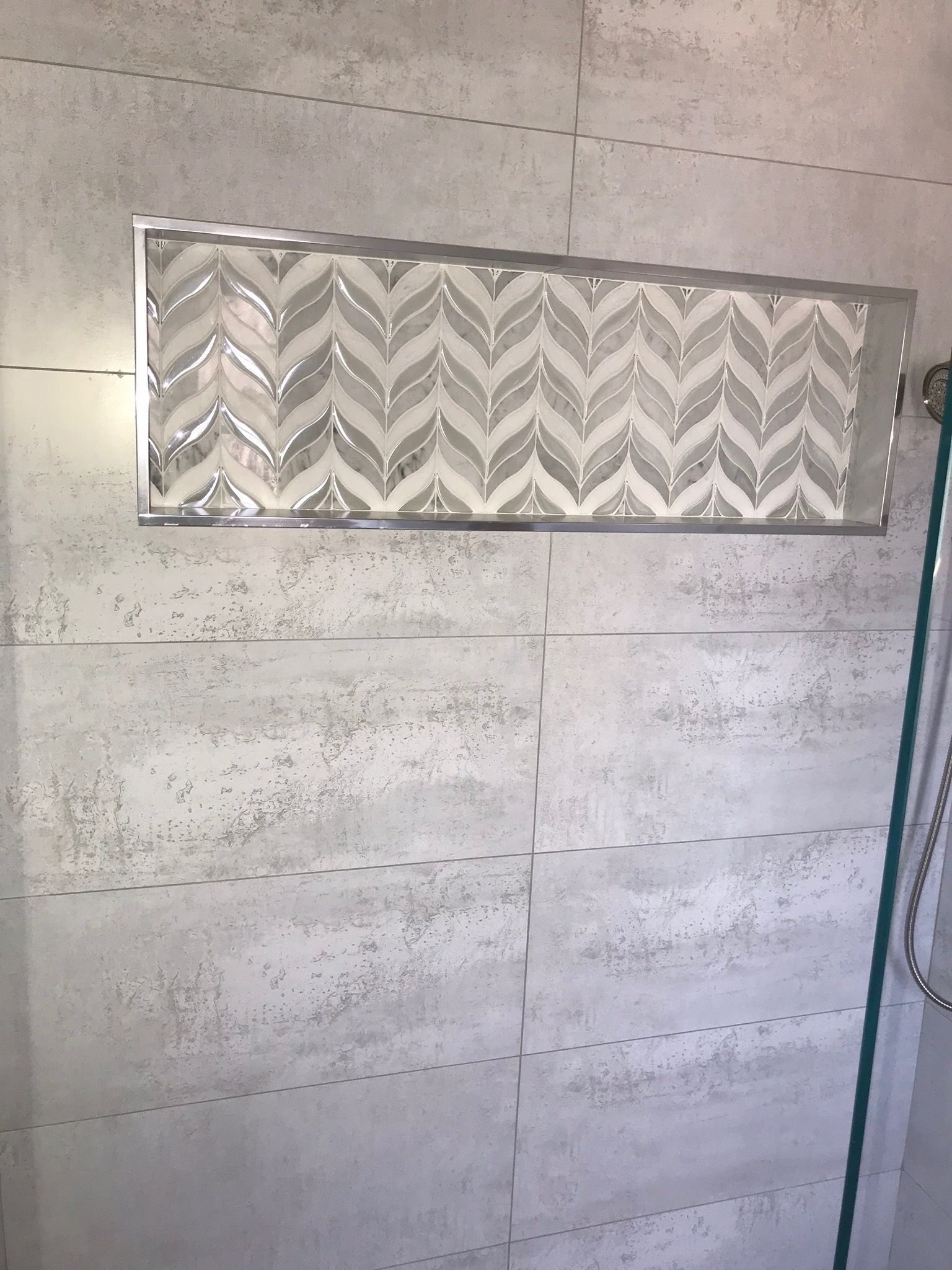 A shower stall with a chevron pattern on the wall.