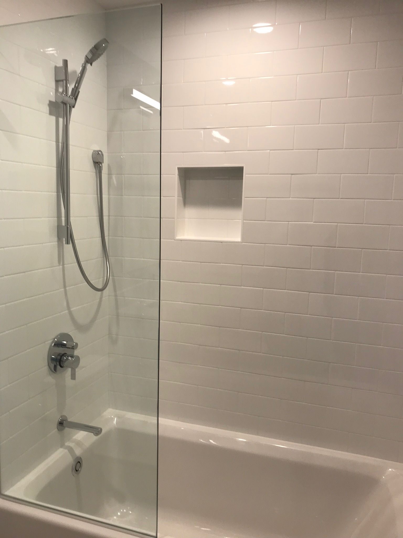 A bathroom with a bathtub and a shower with a glass door.