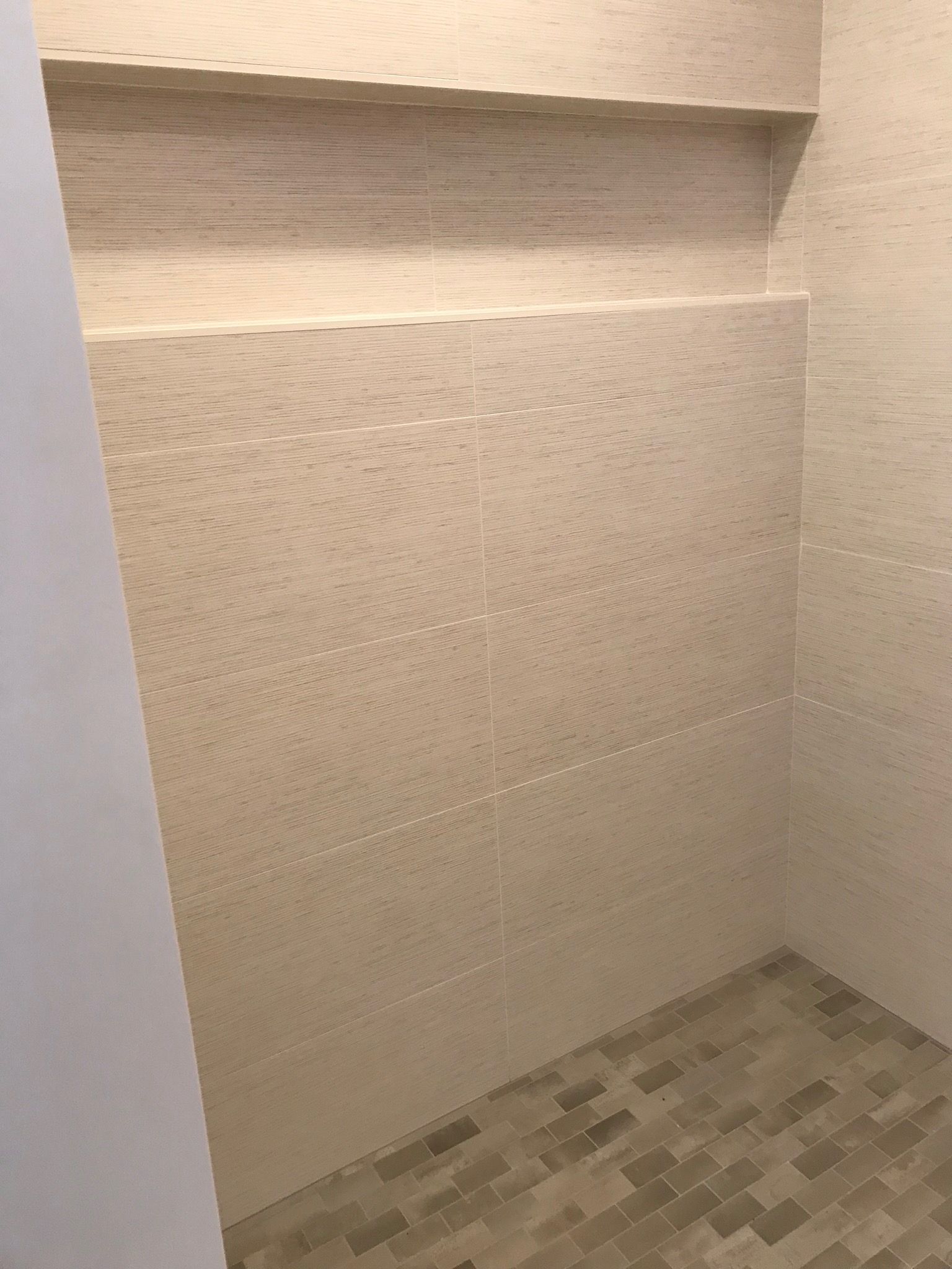 A bathroom with a walk in shower and a shelf in the wall.