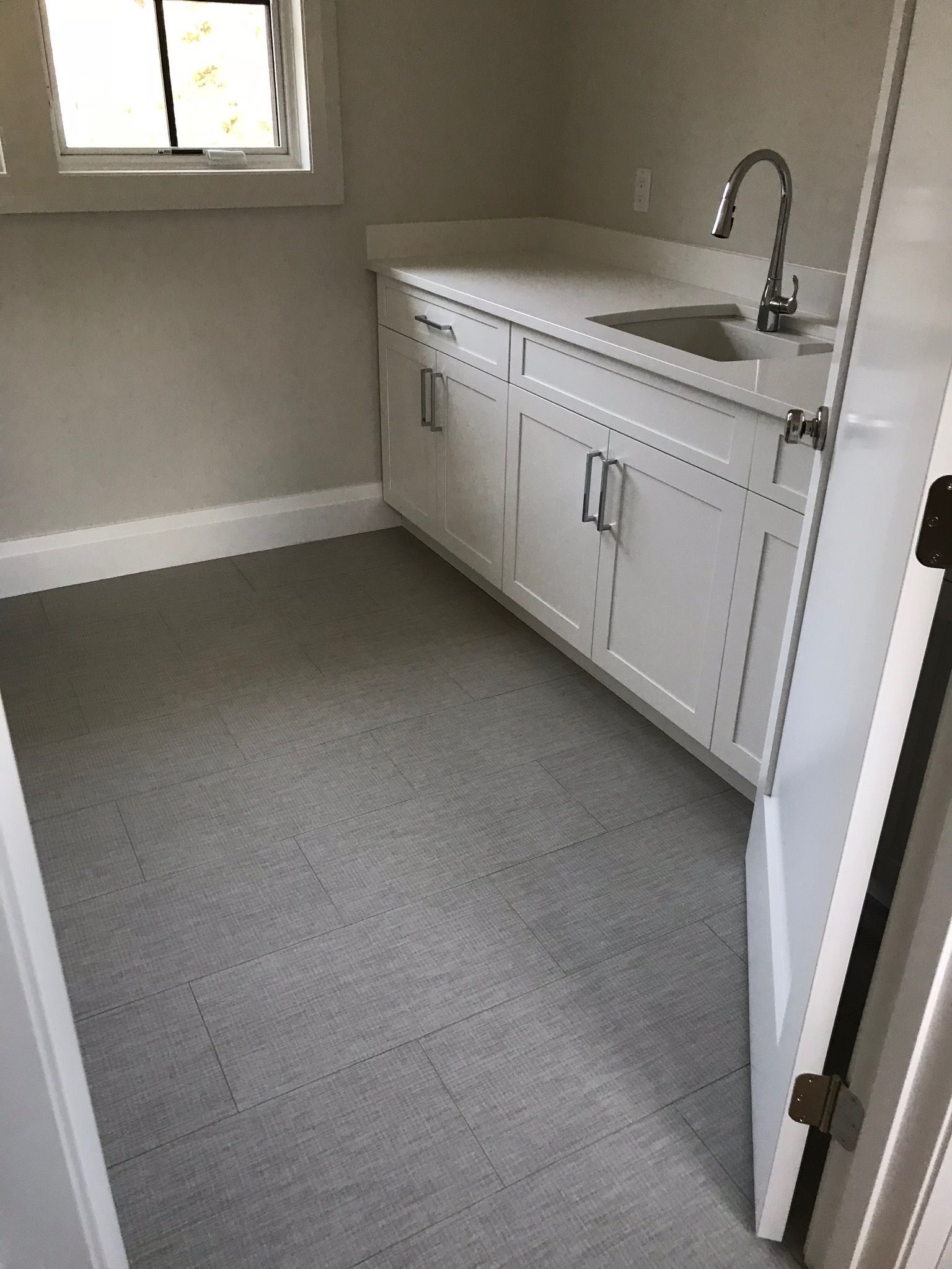 A kitchen with white cabinets , a sink , and a window.