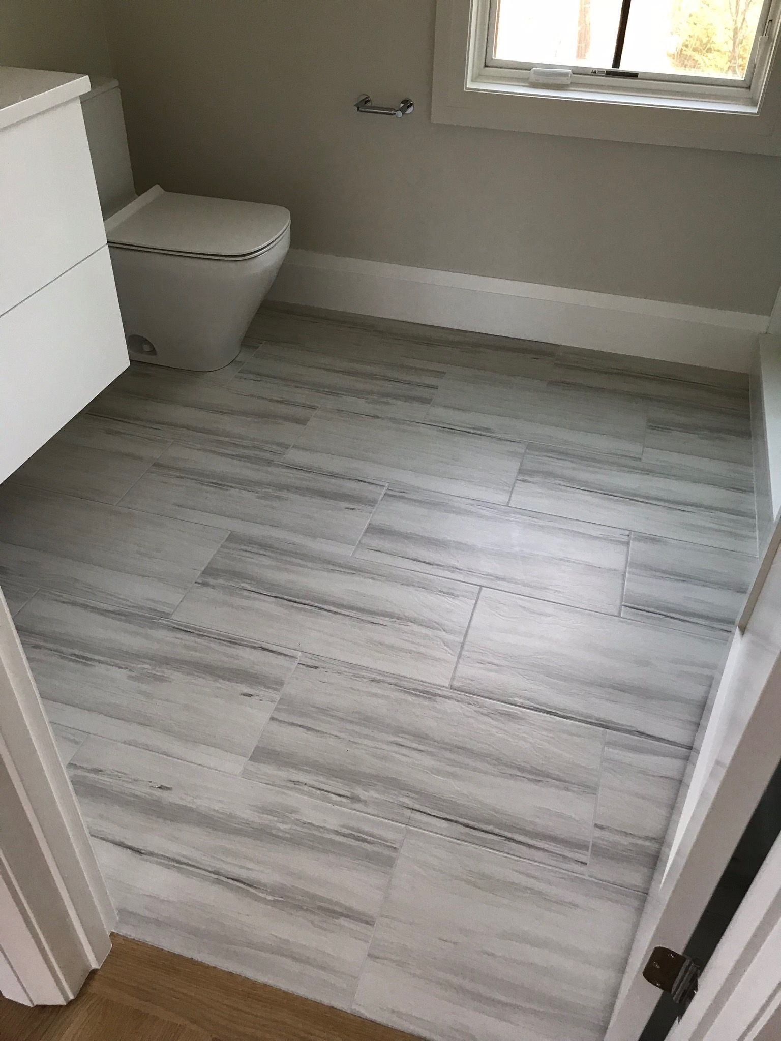 A bathroom with a toilet , sink , and window.