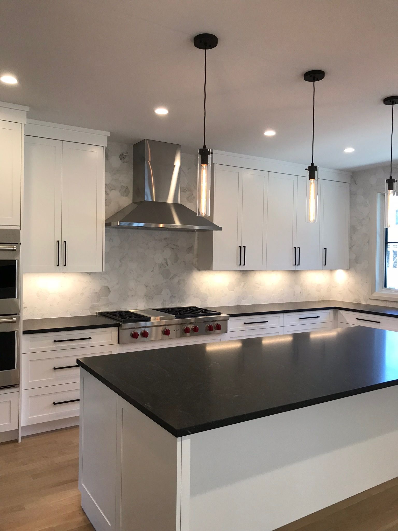 A kitchen with white cabinets and black counter tops