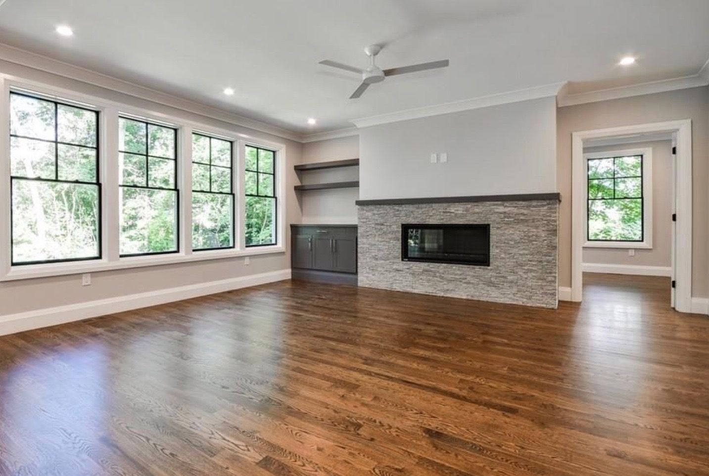An empty living room with hardwood floors and a fireplace.