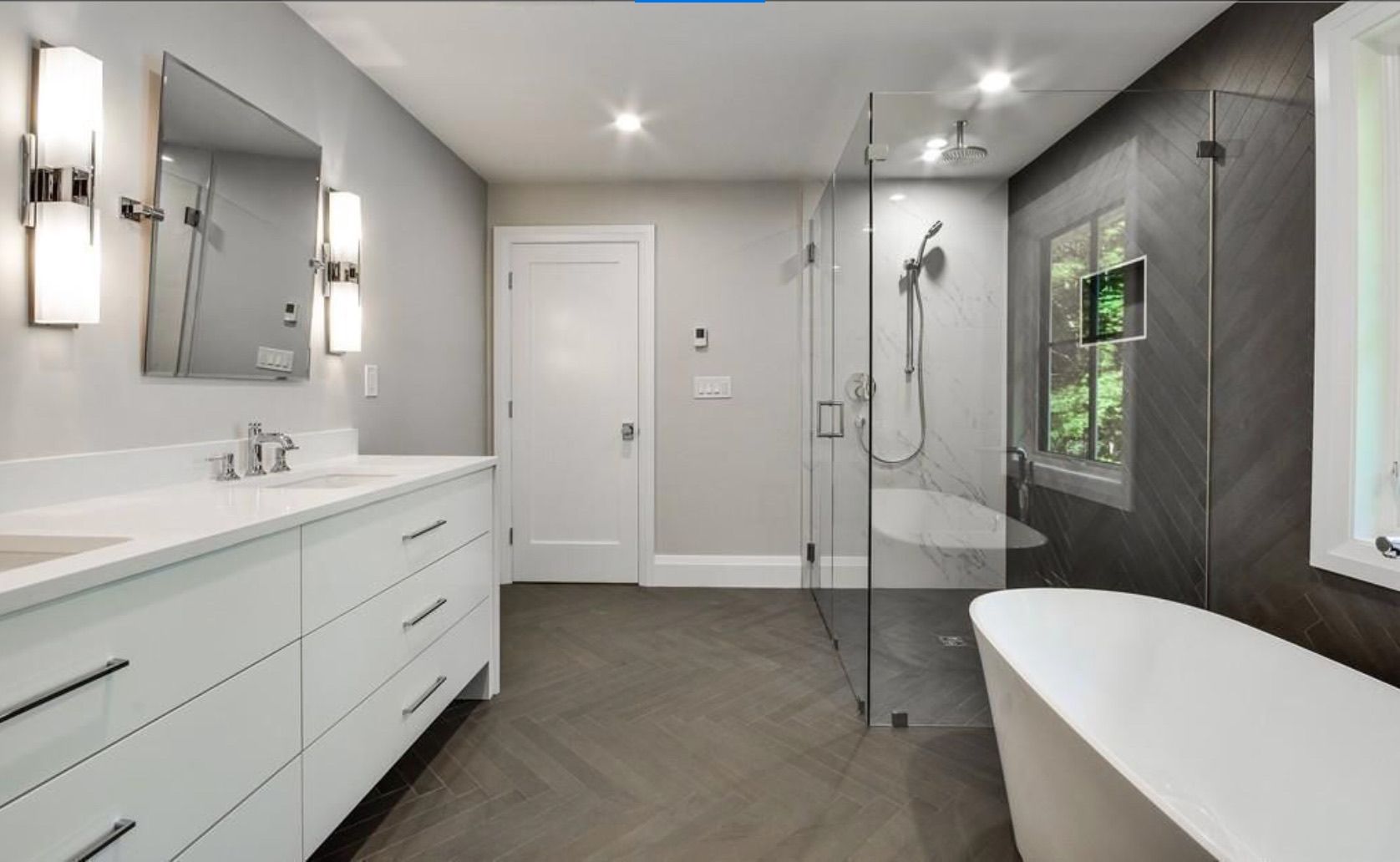 A bathroom with two sinks , a tub , a shower and a mirror.