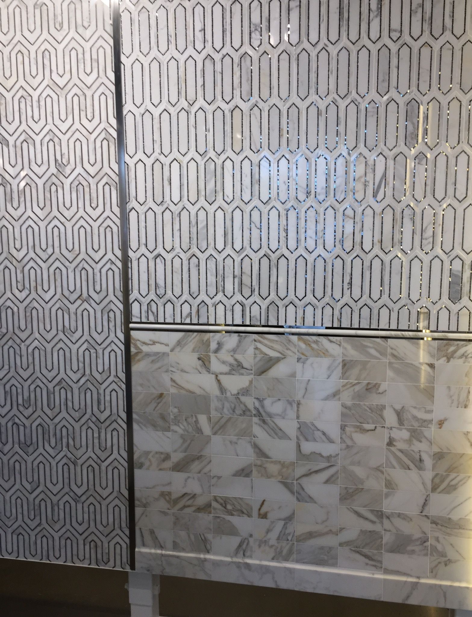 A bathroom with a marble counter top and a geometric pattern on the wall.