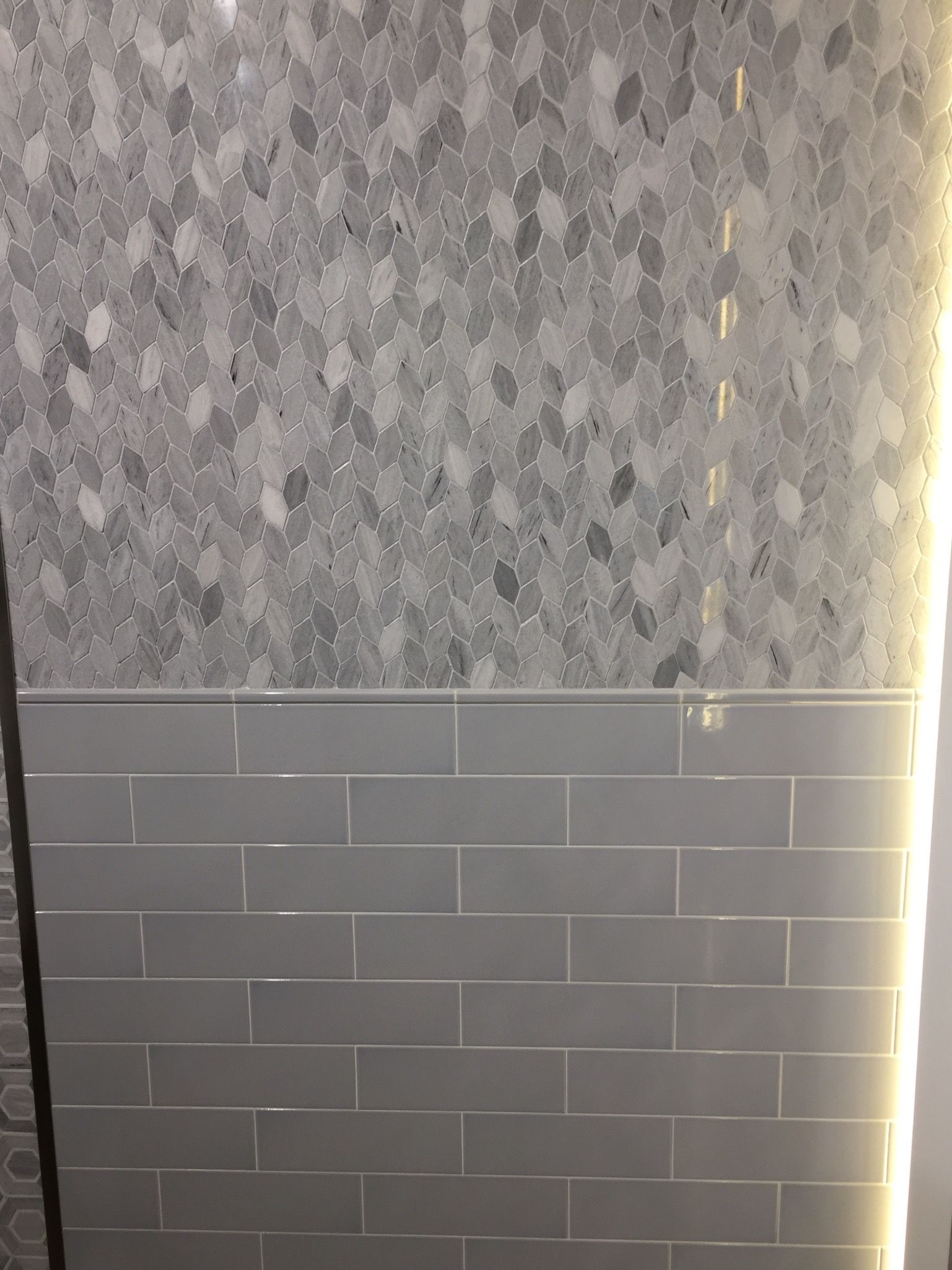 A wall with a lot of tiles on it and a light behind it.