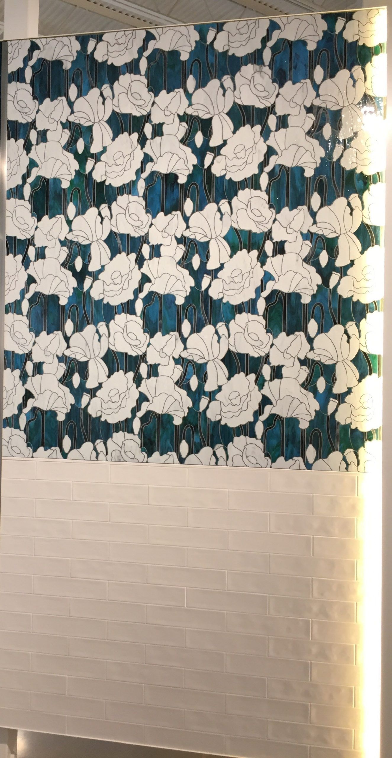 A blue and white floral pattern on a white brick wall.