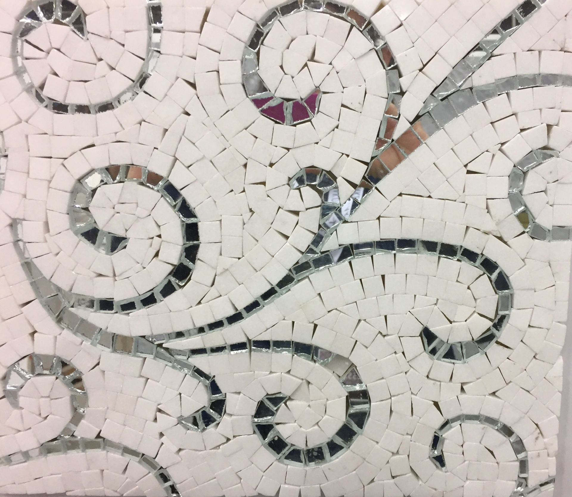 A white and silver mosaic with a swirl design