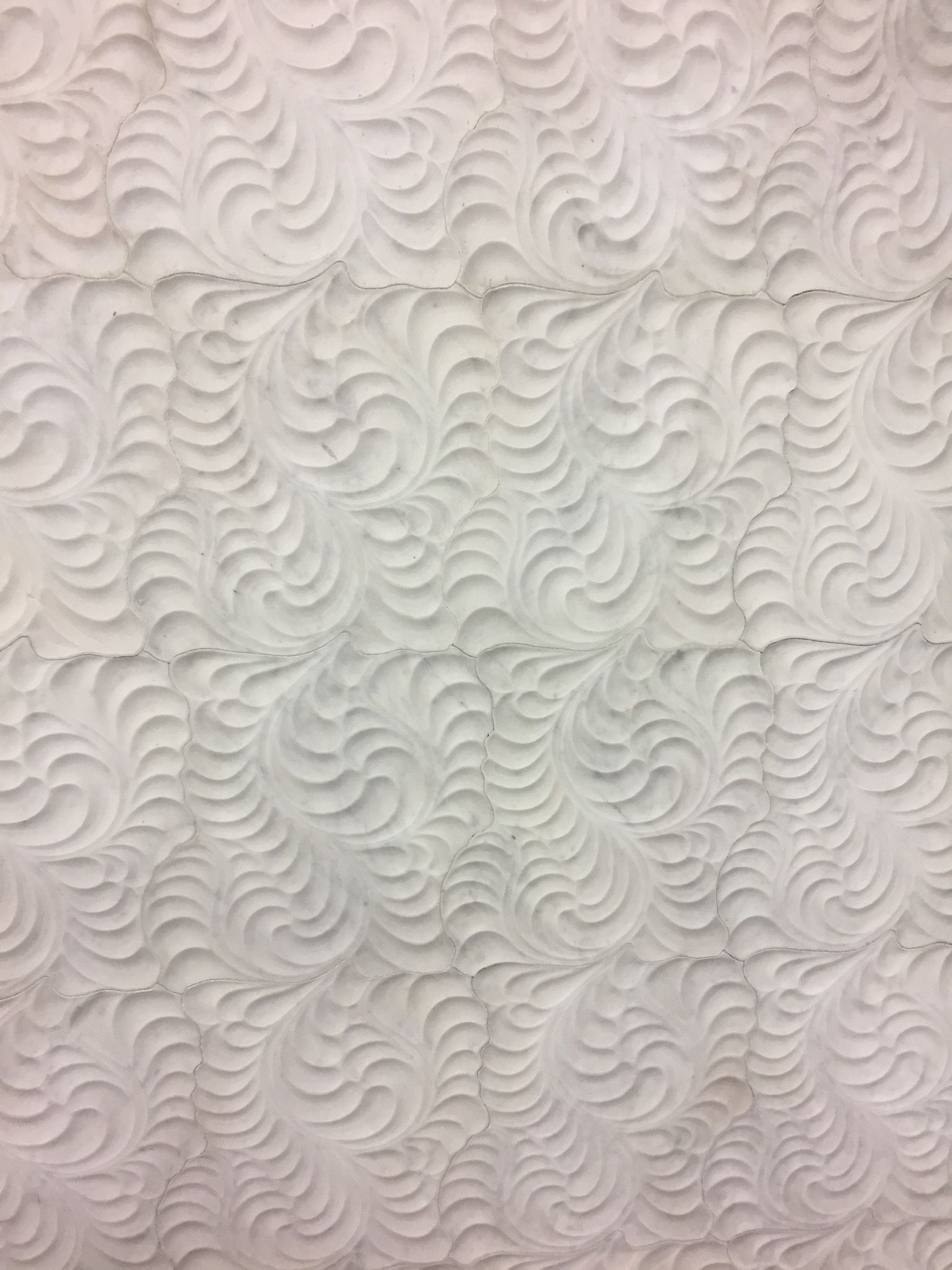 A close up of a white quilt with a pattern on it.