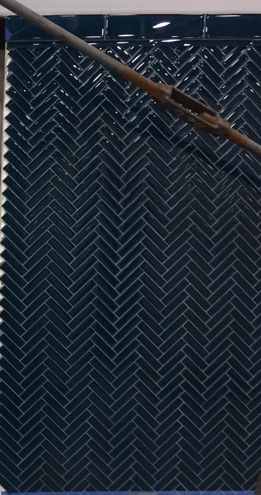 A close up of a blue tile with a herringbone pattern.