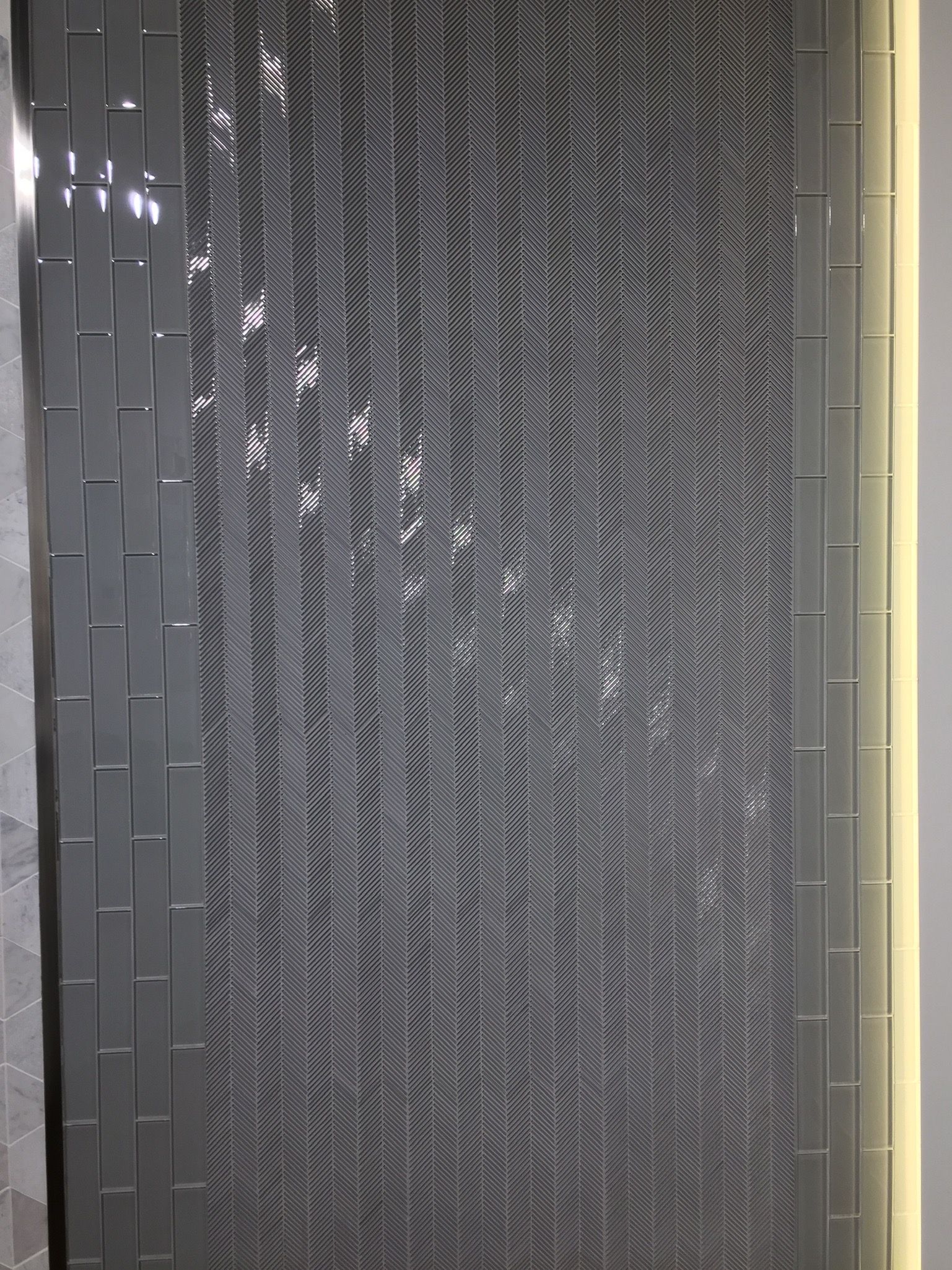A gray tile wall with a chevron pattern and a light behind it.