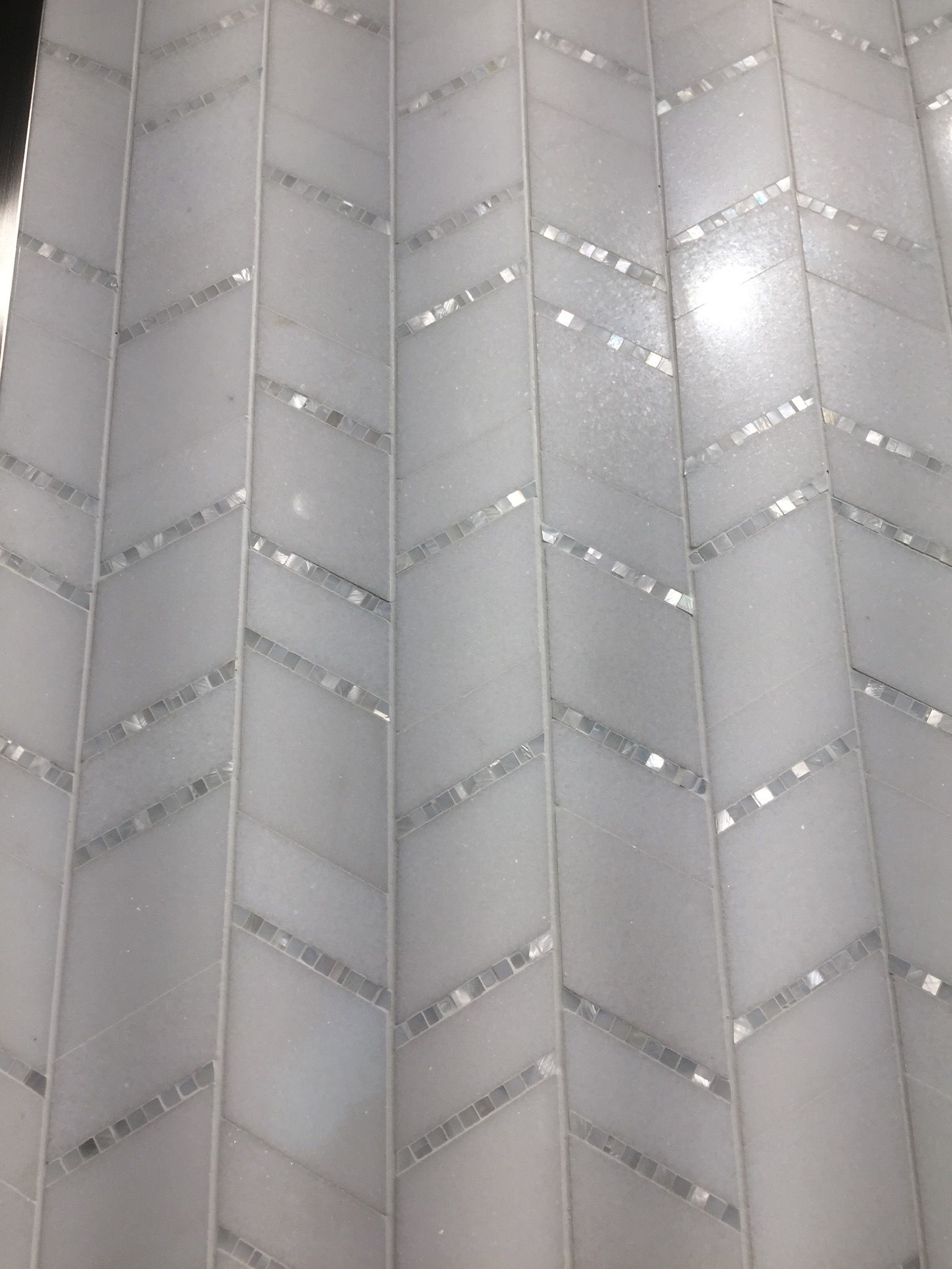 A close up of a white tile wall with a chevron pattern.