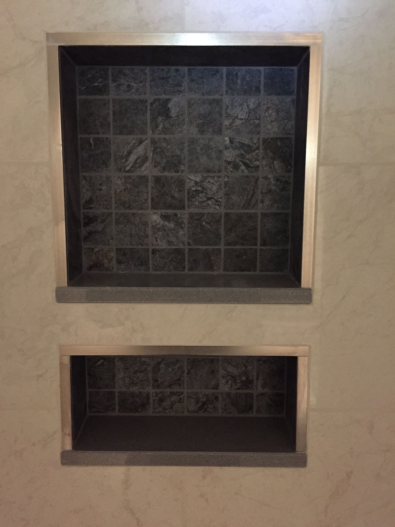 There are two shelves in the wall with tiles on them.