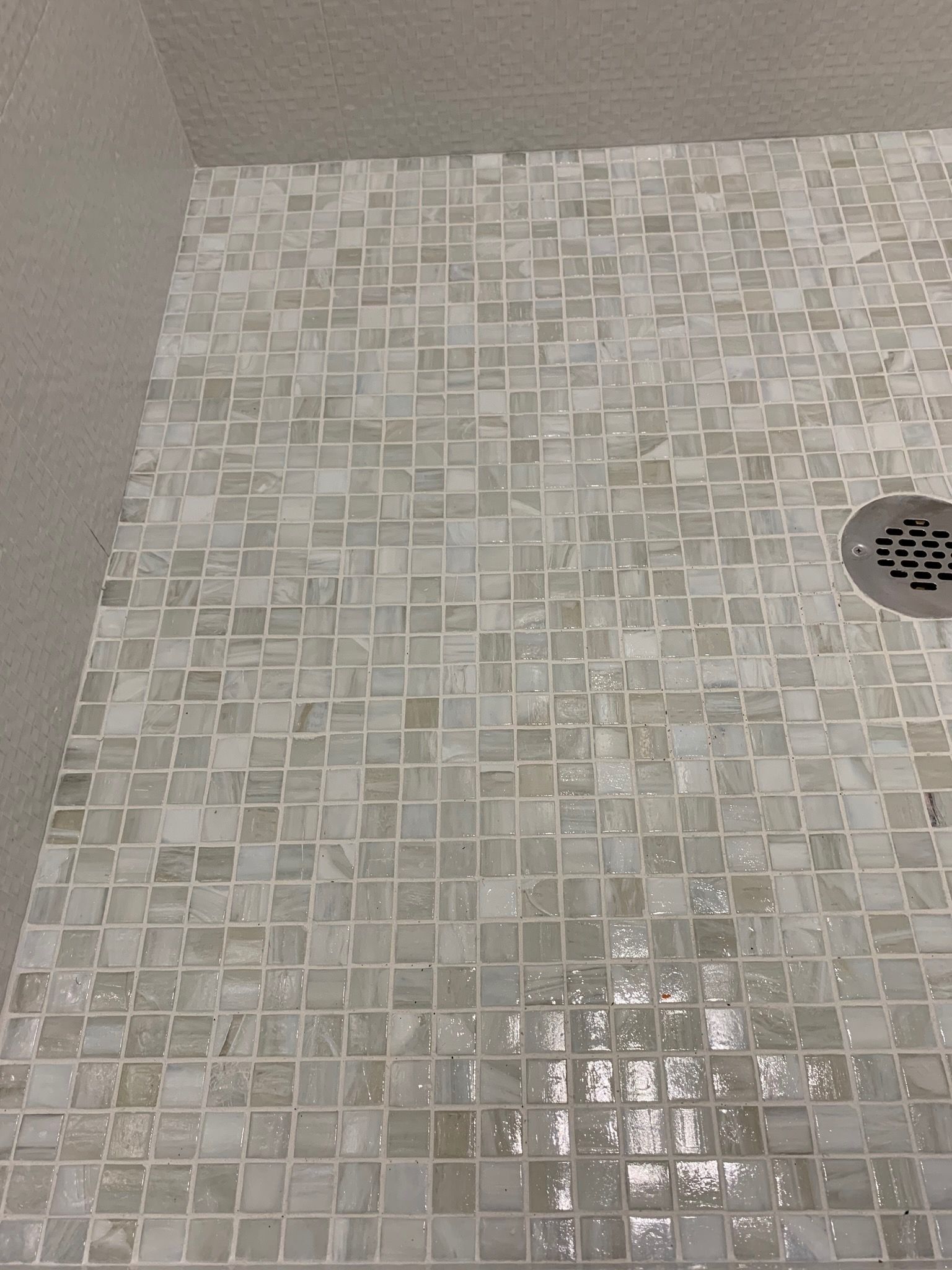 A close up of a tiled shower floor with a drain.