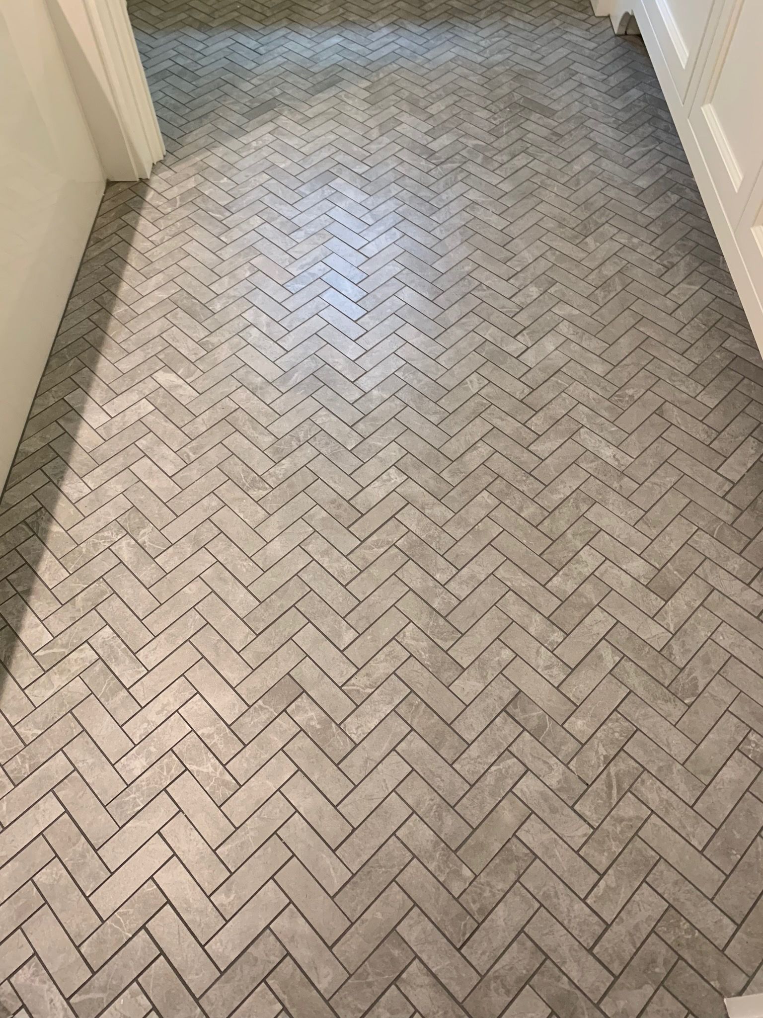 A hallway with a herringbone pattern on the floor.