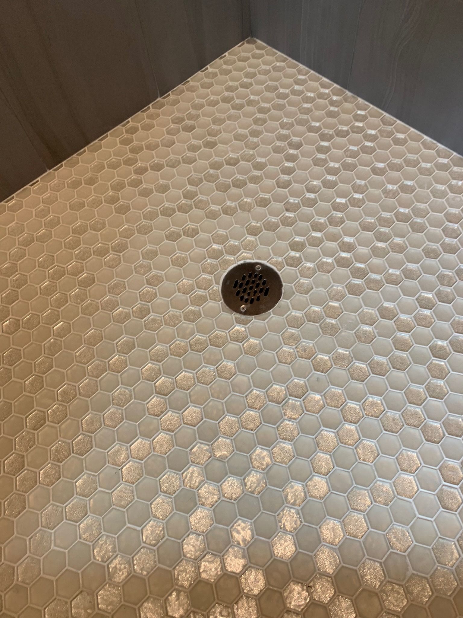 A close up of a shower floor with a drain.
