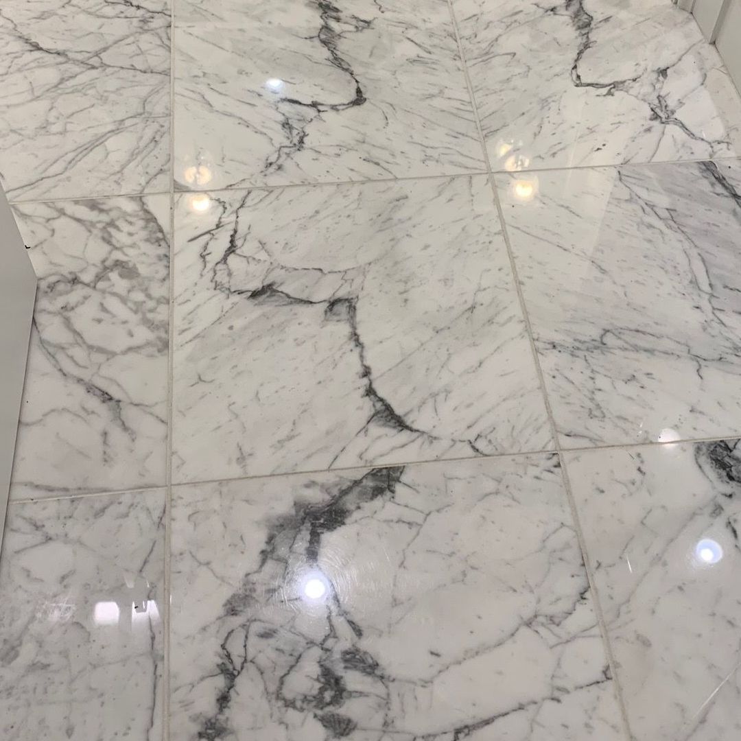 A close up of a white marble floor in a bathroom.