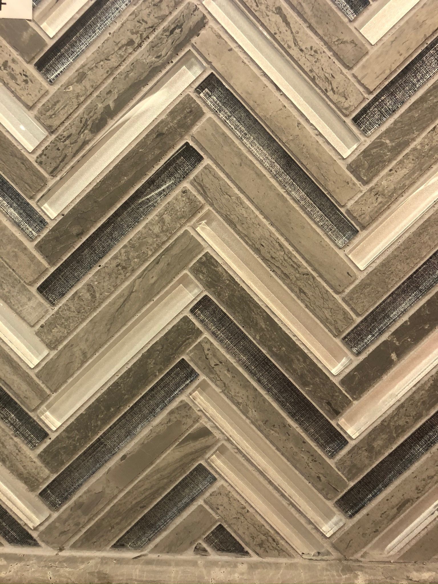 A close up of a herringbone tile pattern on a wall.