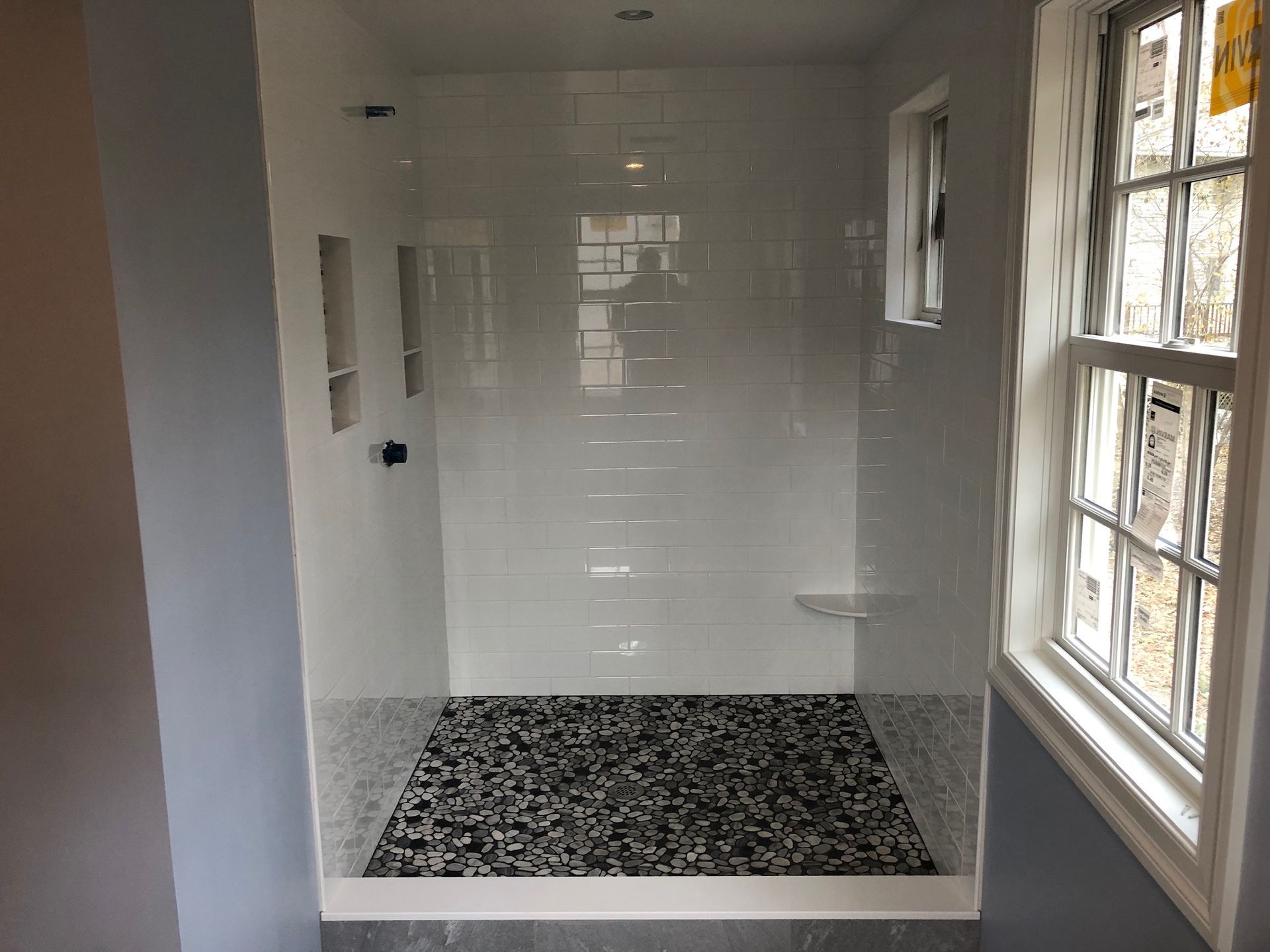 A bathroom with a walk in shower and a window