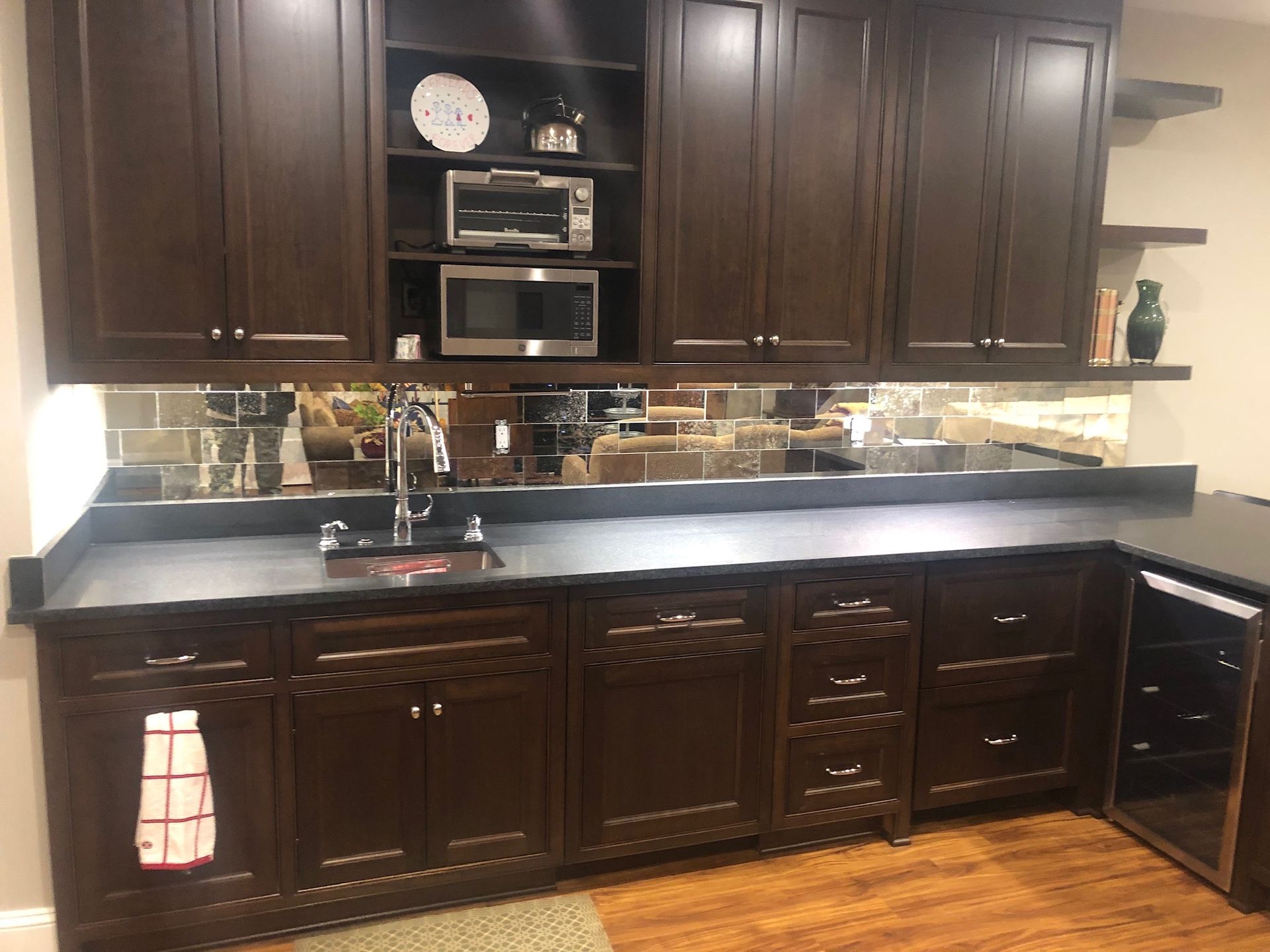 A kitchen with wooden cabinets , a sink , a microwave and a refrigerator.