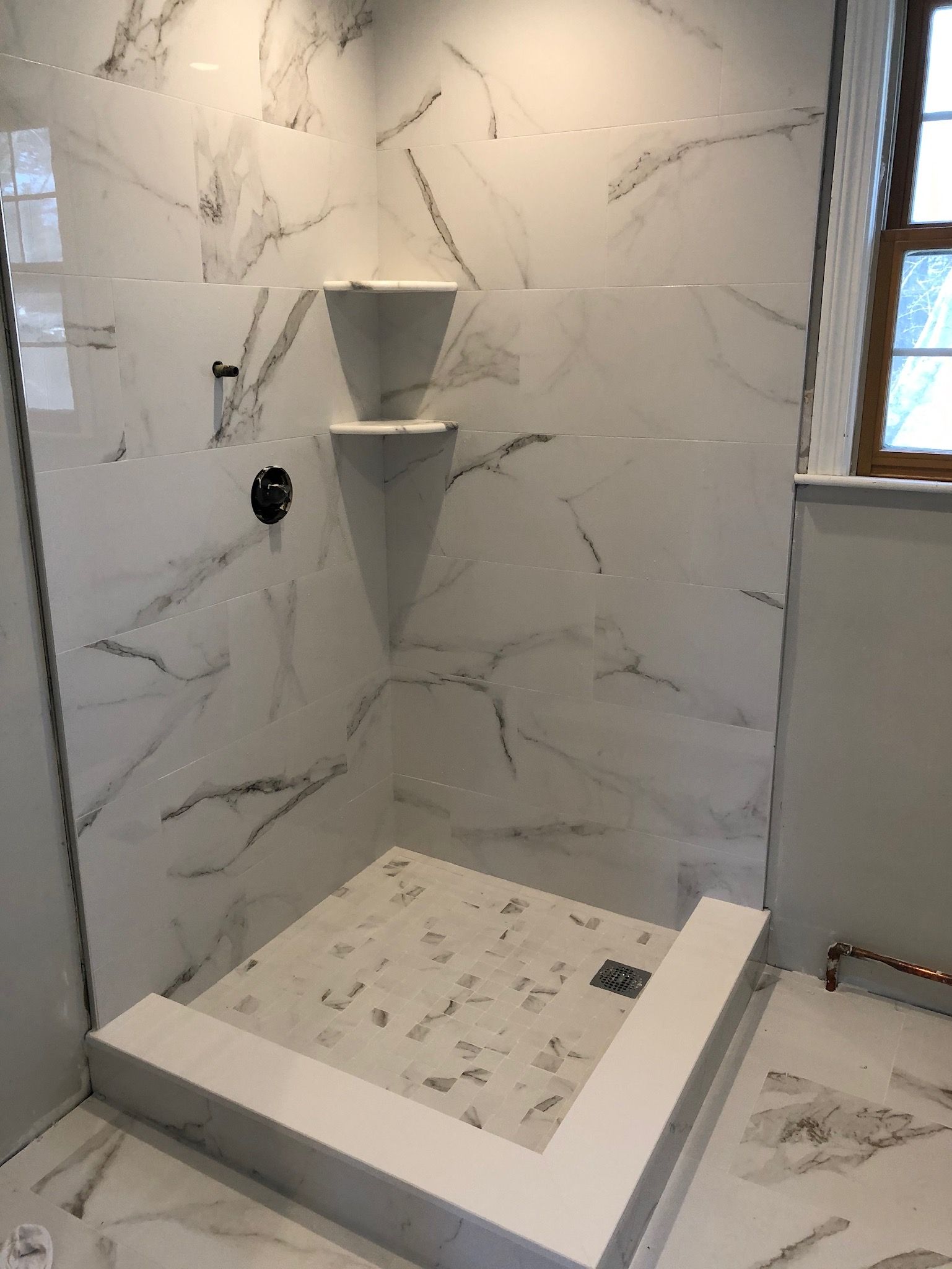 A bathroom with a walk in shower and a window.