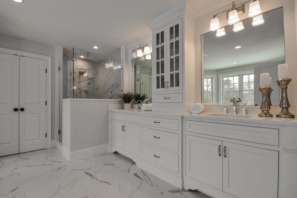 A bathroom with two sinks , two mirrors , and a walk in shower.