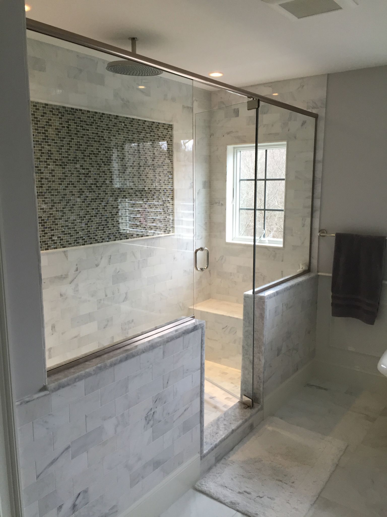 A bathroom with a walk in shower and a window.