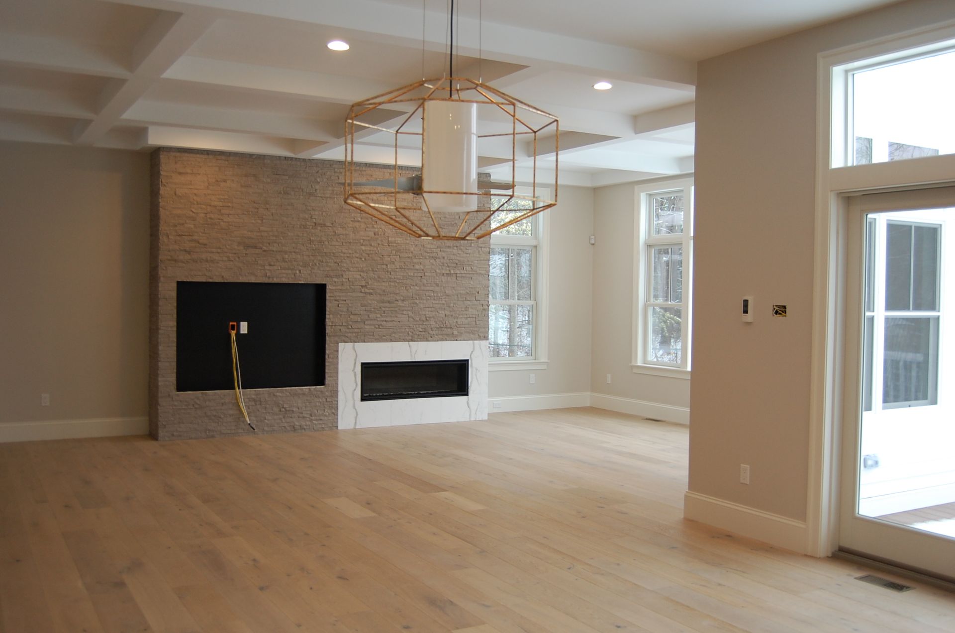 An empty living room with a fireplace and a chandelier.