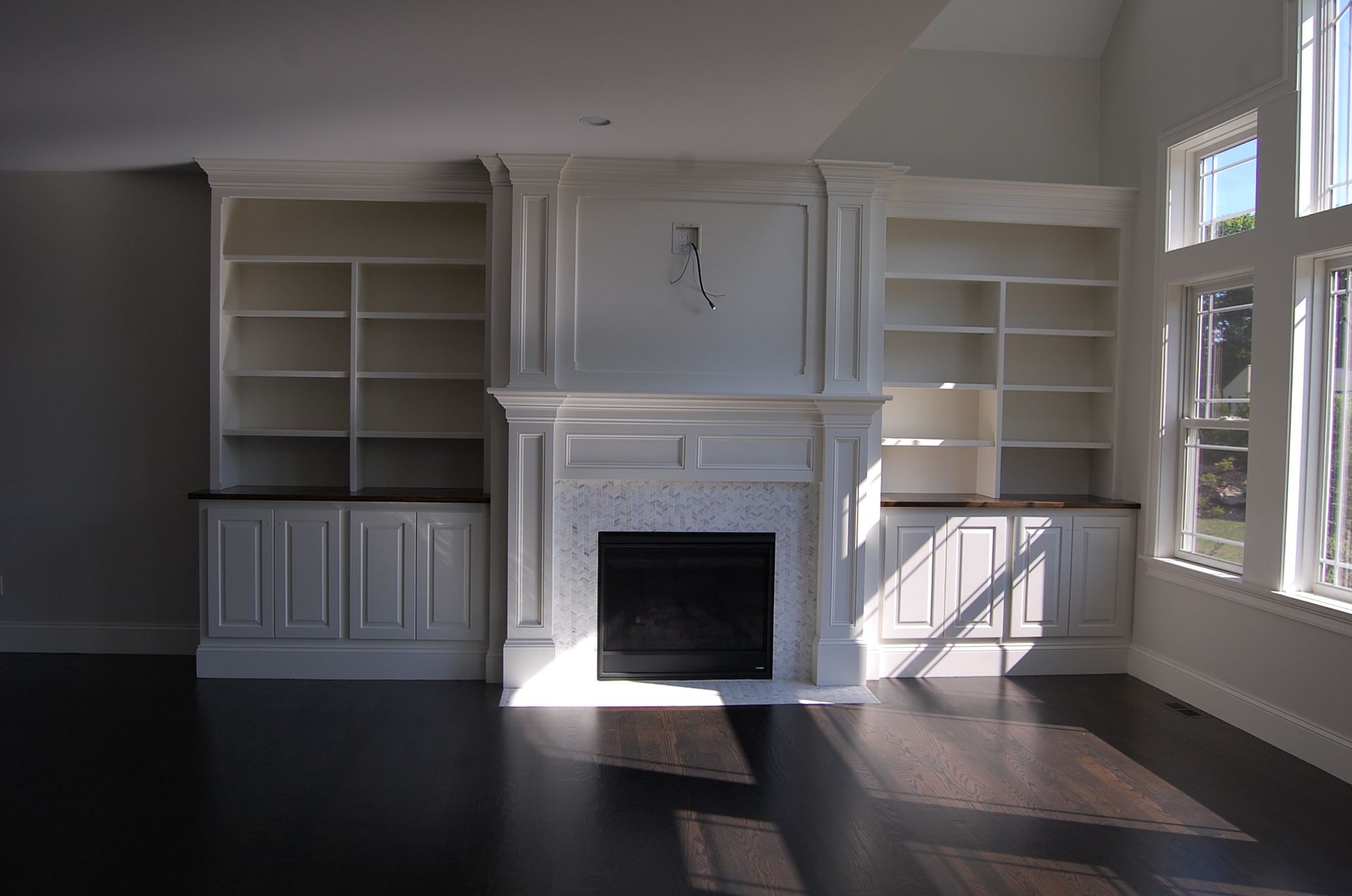 An empty living room with a fireplace and shelves