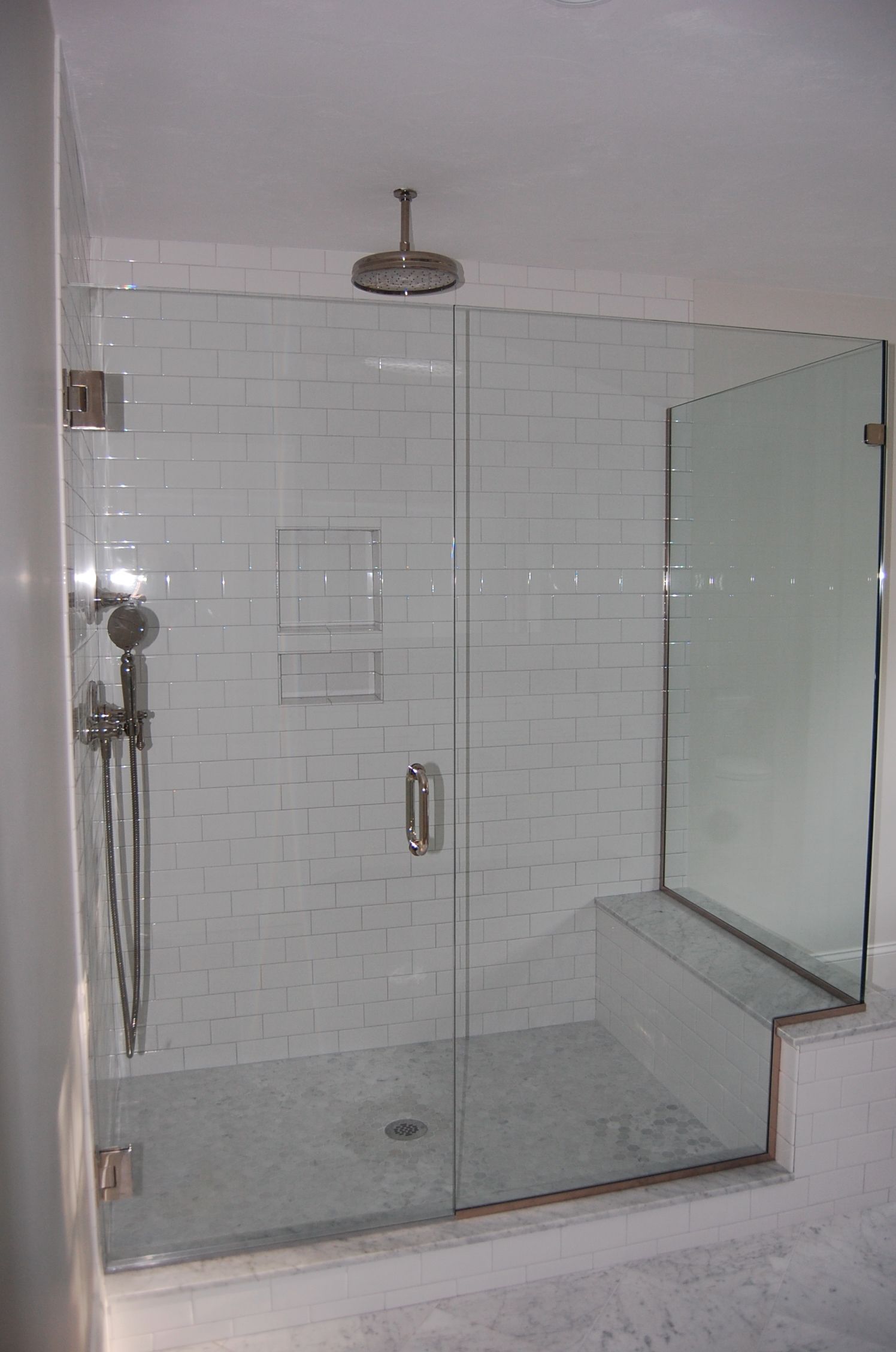 A bathroom with a walk in shower with a glass door.