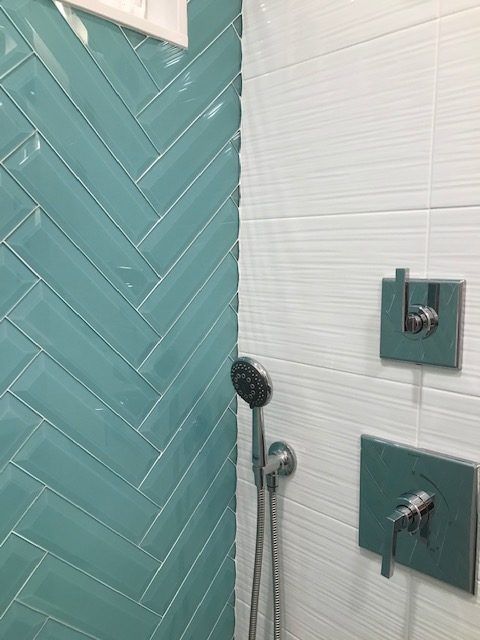 A bathroom with blue tiles and a shower head.