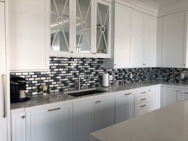A kitchen with white cabinets , a sink , and a coffee maker.