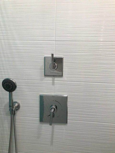 A close up of a shower head and faucet in a bathroom.