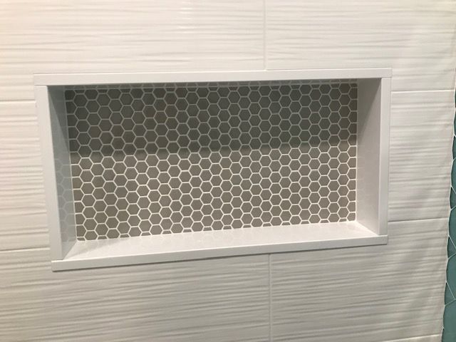 A shower niche with honeycomb tiles in a bathroom.