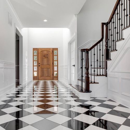 A hallway with a checkered floor and stairs in a house.