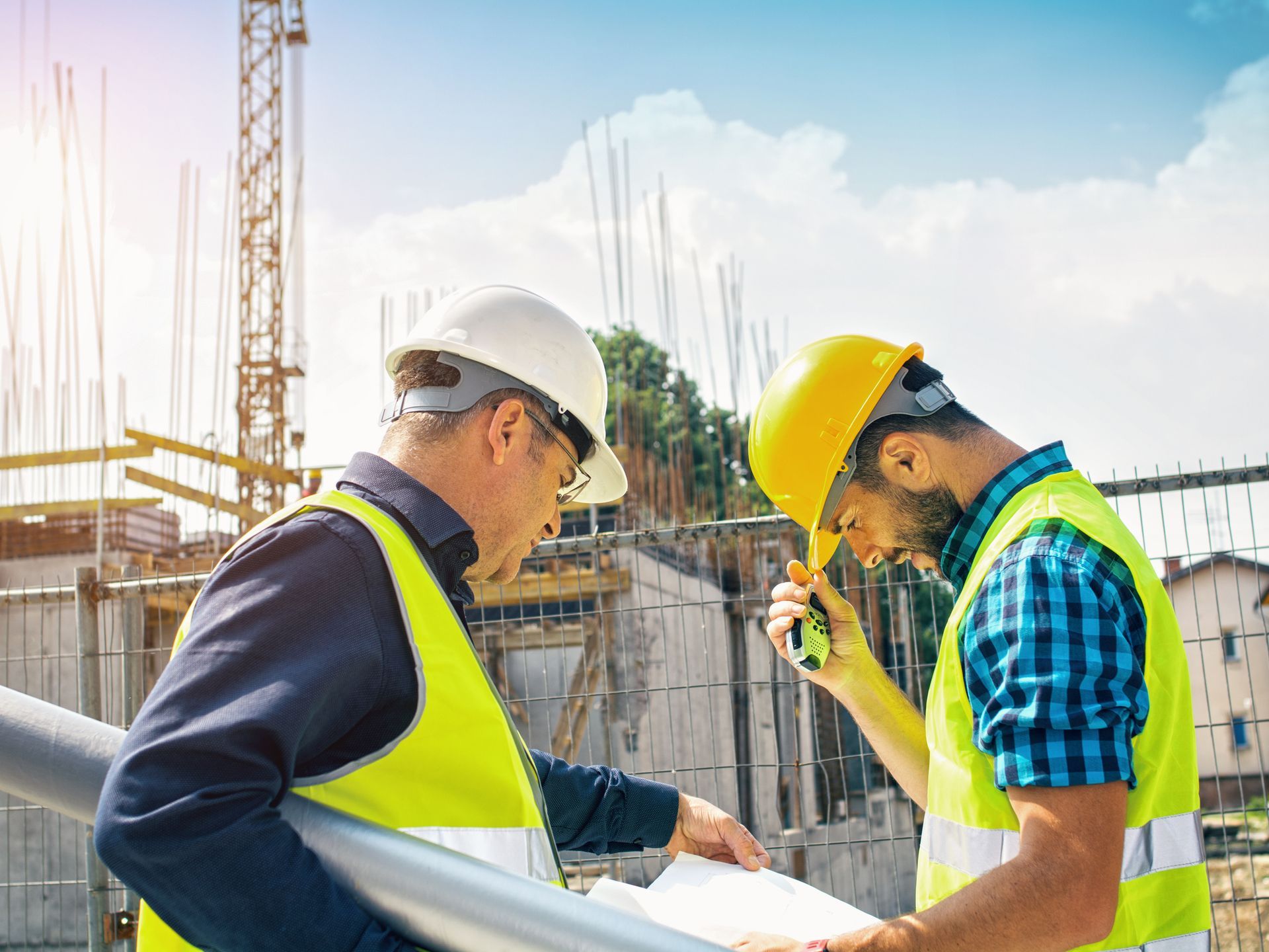 Close-up of two construction workers reviewing blueprints at a site during a new home build project. Close-up of two construction workers reviewing blueprints at a site during a new home build project.