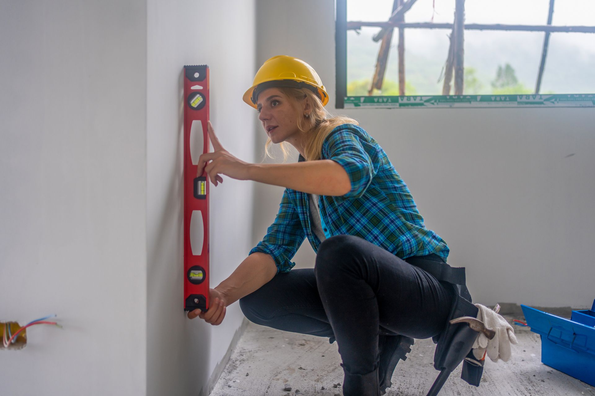 Construction worker insulating house wall with styrofoam insulatuion sheet.