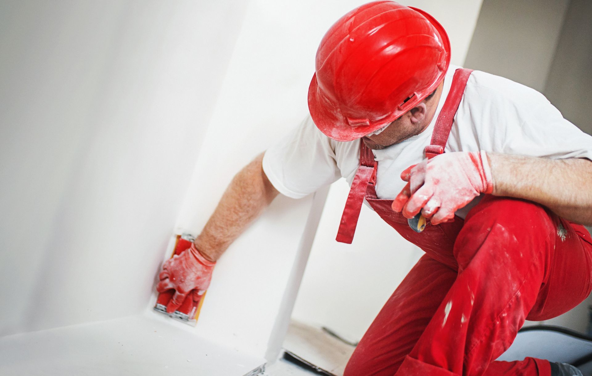 Commercial dry wall contractor sanding a smooth drywall surface during building renovation.