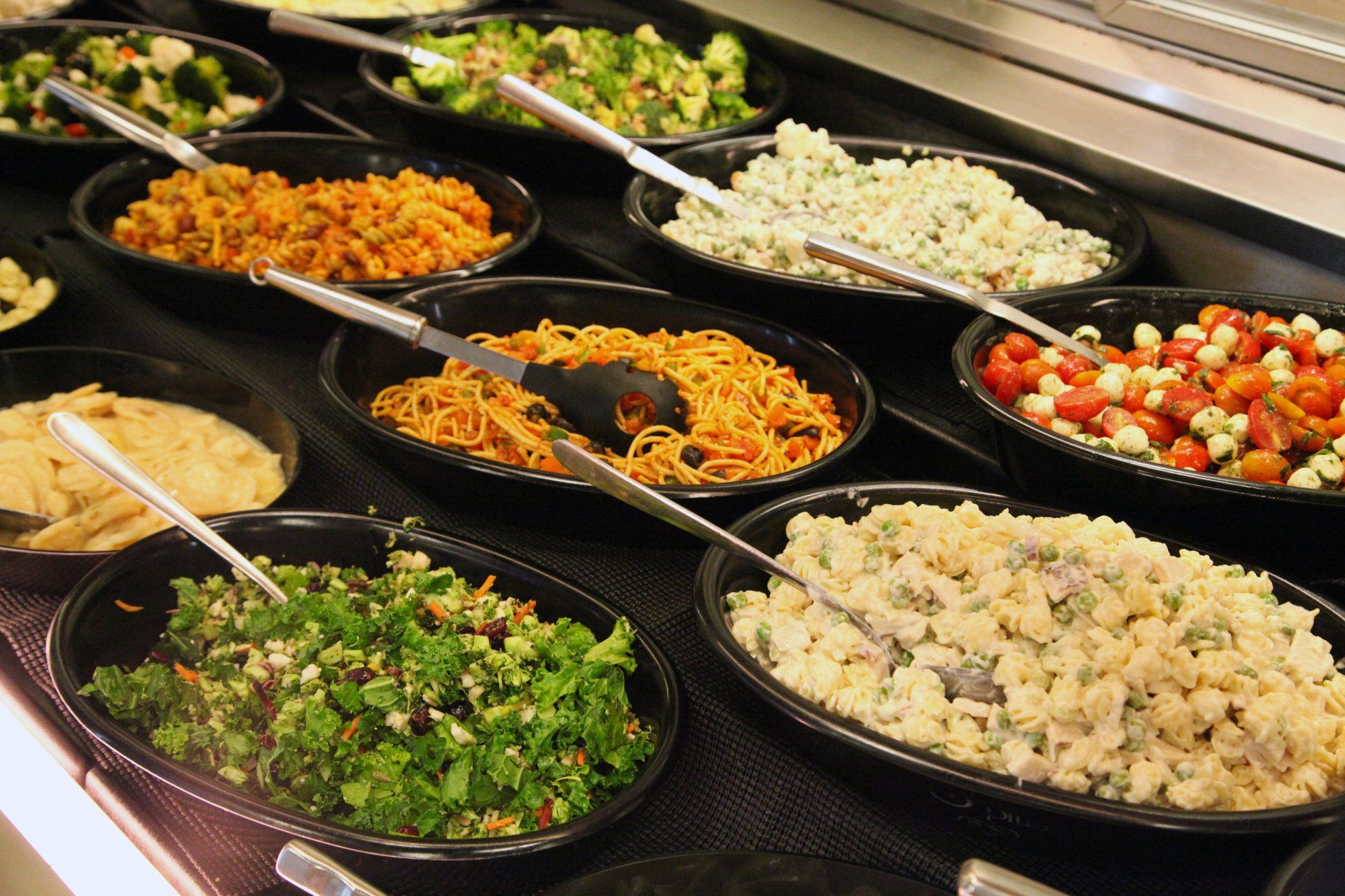 A variety of salads are displayed on a buffet line