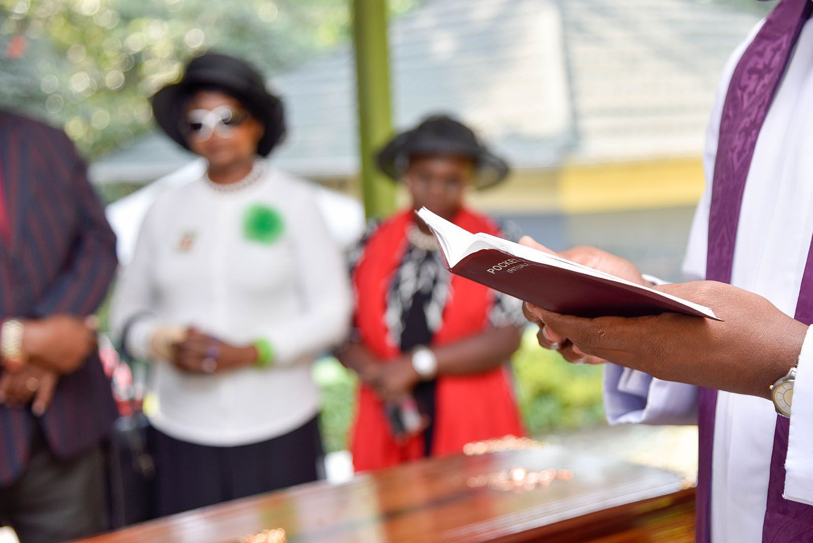 Three people fishing off a wooden dock: a child, an adult, and an older person. The adult holds the child.